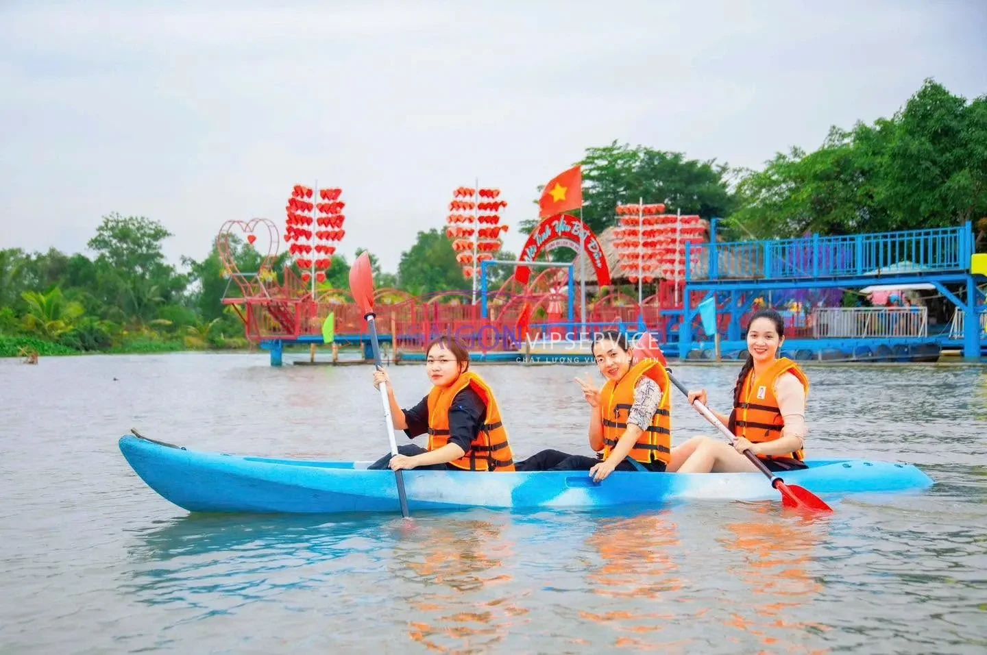 Du khách mặc áo phao tham gia trải nghiệm chèo thuyền trên sông tại Làng du lịch Tre Việt