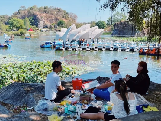 Nhóm du khách đang cắm trại, tổ chức ăn uống dã ngoại trên bãi cỏ ven hồ nước mát mẻ tại Khu du lịch Bửu Long.