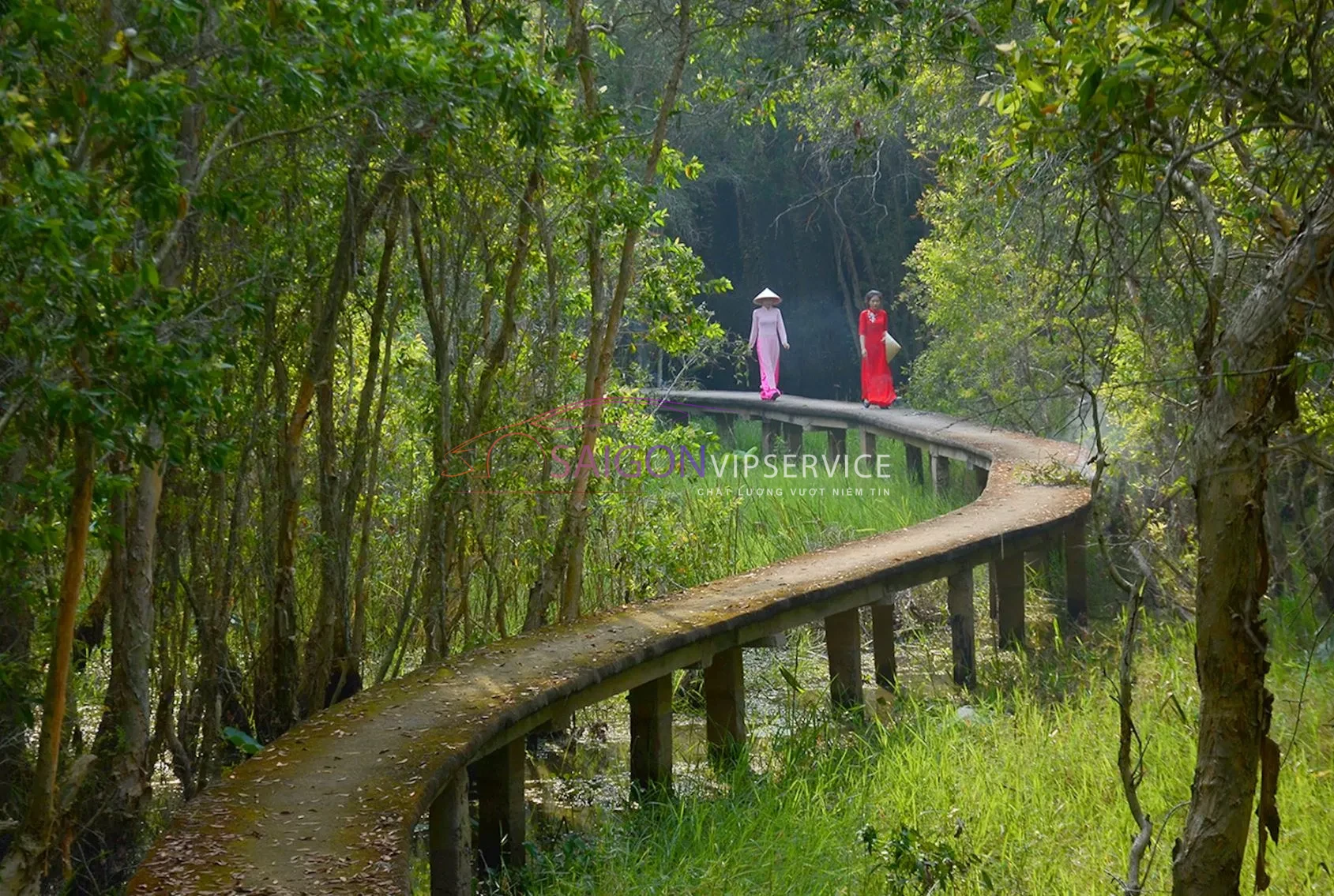 Du khách mặc áo dài dạo bước trên con đường bê tông xuyên rừng tràm rợp bóng mát tại Làng nổi Tân Lập