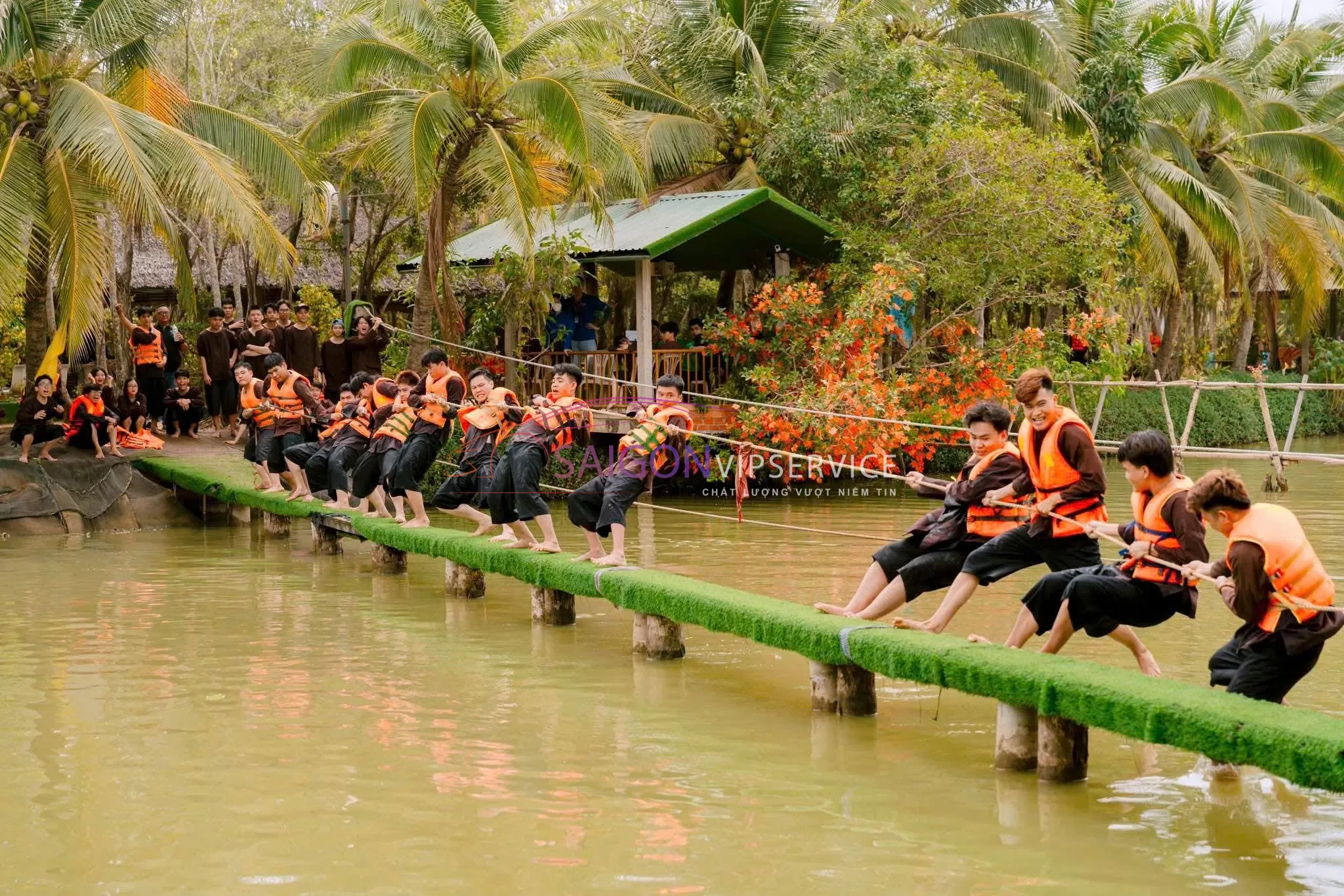 Các đoàn khách tham gia hoạt động team building với trò chơi thăng bằng và kéo co trên sông tại Khu du lịch Lan Vương.
