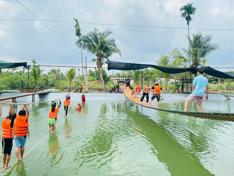 Nhóm du khách mặc áo phao đang chinh phục thử thách đi qua cầu treo vượt hồ nước tại Khu du lịch Song Long.